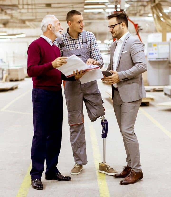 Three men standing together on a factory floor.