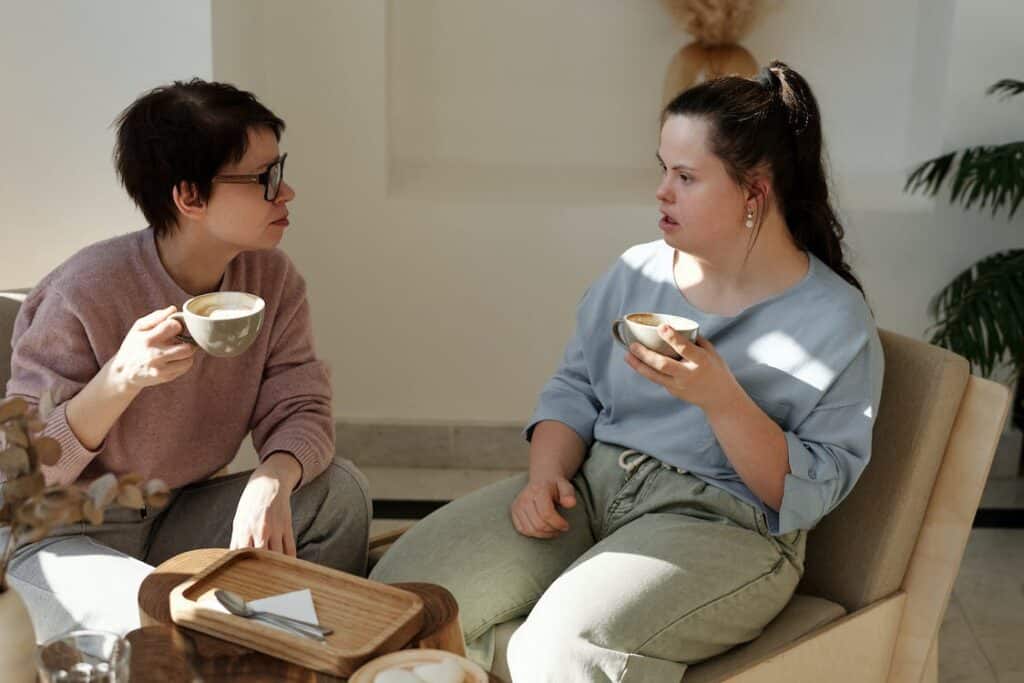 Two people are having a conversation over coffee in an office setting. The person on the left is listening intently to the person on the right. Active listening is an important part of the solution-focused approach to supported employment.