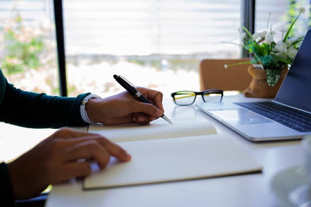 A person is sitting at a desk by a window in an office, writing in a notebook with a laptop in front of them. CASE courses enable employers to engage in ongoing professional development when it best aligns with their schedule.